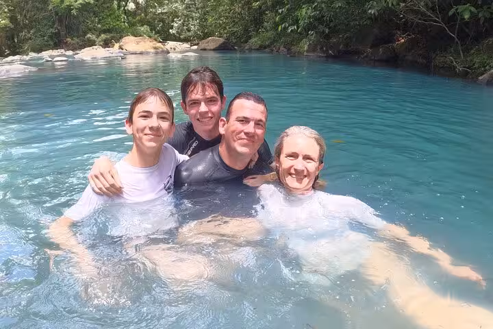 Group enjoying a refreshing swim in the vibrant blue waters of the natural pool at Río Celeste, Costa Rica.