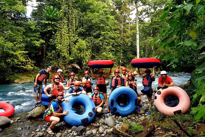 Group of excited tubers pose with tubes by Rio Celeste, ready for an exhilarating nature adventure.