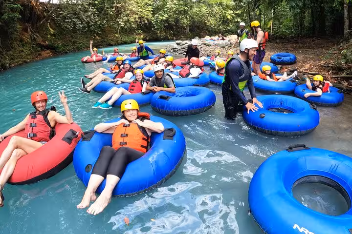 Group enjoying tubing adventure on Rio Celeste's turquoise waters during a full-day hiking tour in Costa Rica.