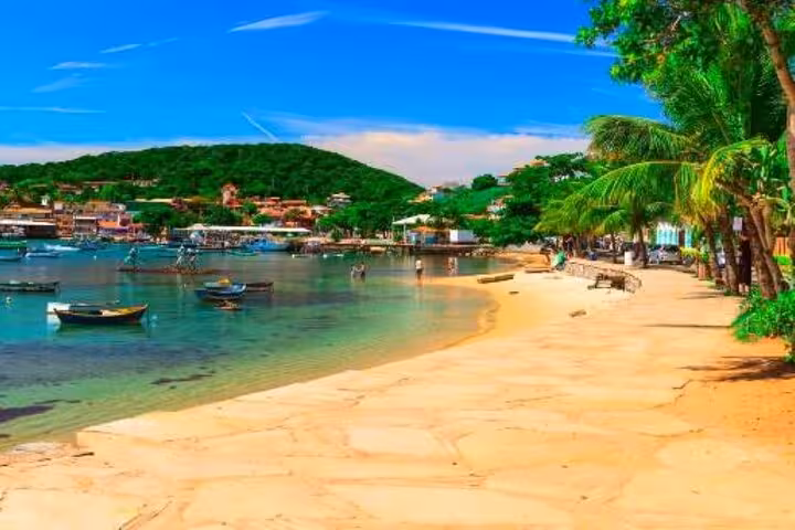 Scenic view of Buzios beach with clear blue waters, lush greenery, and anchored boats ideal for Rio de Janeiro travelers.