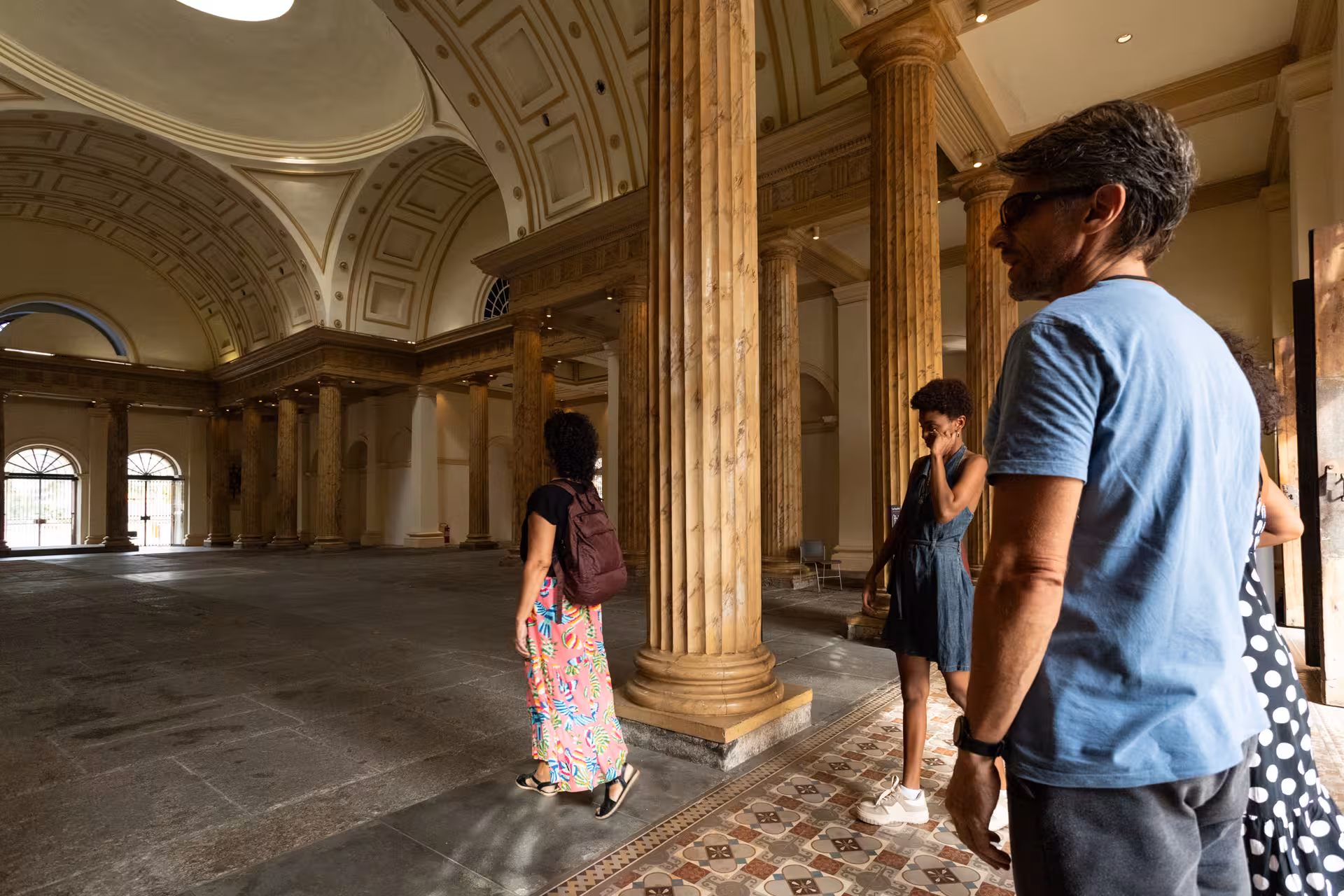 Travelers explore a grand historic hall on a Rio de Janeiro city centre pedicab tour with local guide