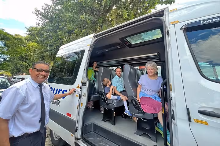 Friendly driver welcomes passengers aboard van for shared transfer from Rio de Janeiro to Paraty.