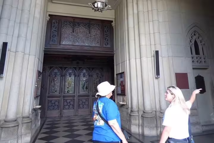 Tourists explore a historic church entrance during Rio's Downtown Walking Tour, showcasing intricate architecture.