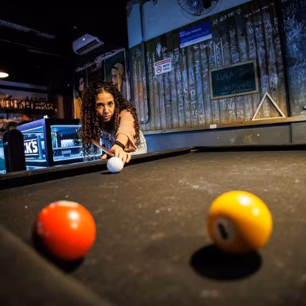 Woman playing pool in a lively Rio bar, capturing the vibrant energy of the gay nightlife and samba scene.
