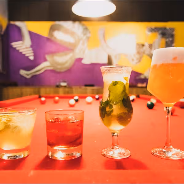Colorful cocktails on a pool table set the scene for a vibrant Rio Gay Nightlife Experience with Samba music.