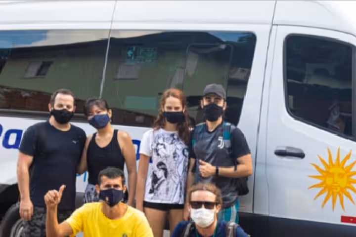 Group of travelers wearing masks ready for Rio de Janeiro shuttle to Ilha Grande near comfortable van.