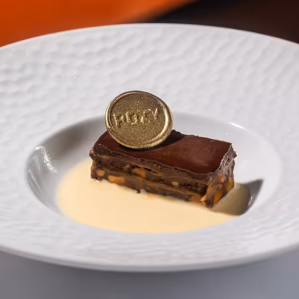 Decadent chocolate dessert garnished with a gold coin at Roxy Copacabana's cultural dinner experience.