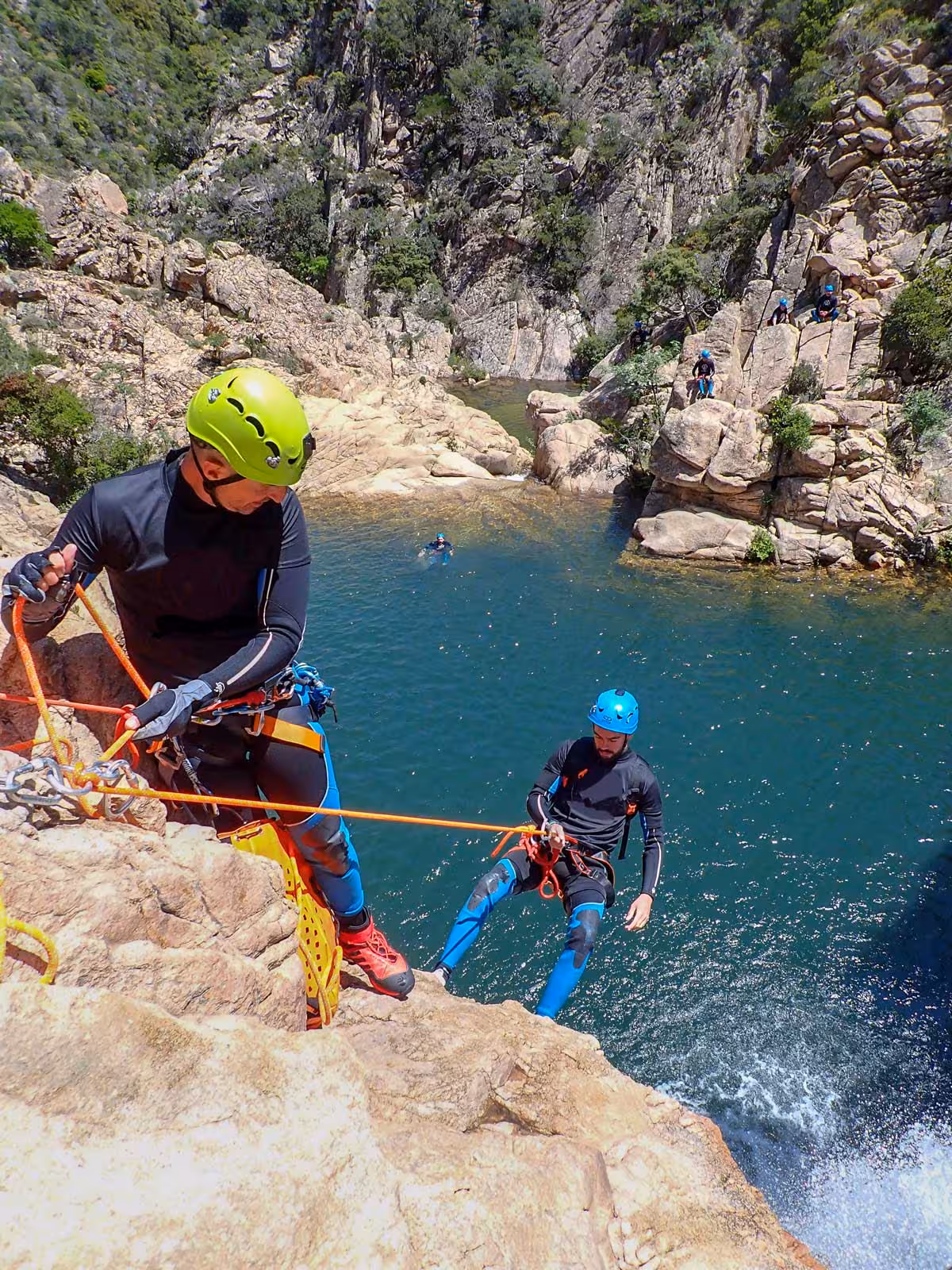 Two thrill-seekers abseiling down a rock face at Rio Pitrisconi, San Teodoro, showcasing outdoor adventure in Sardinia.