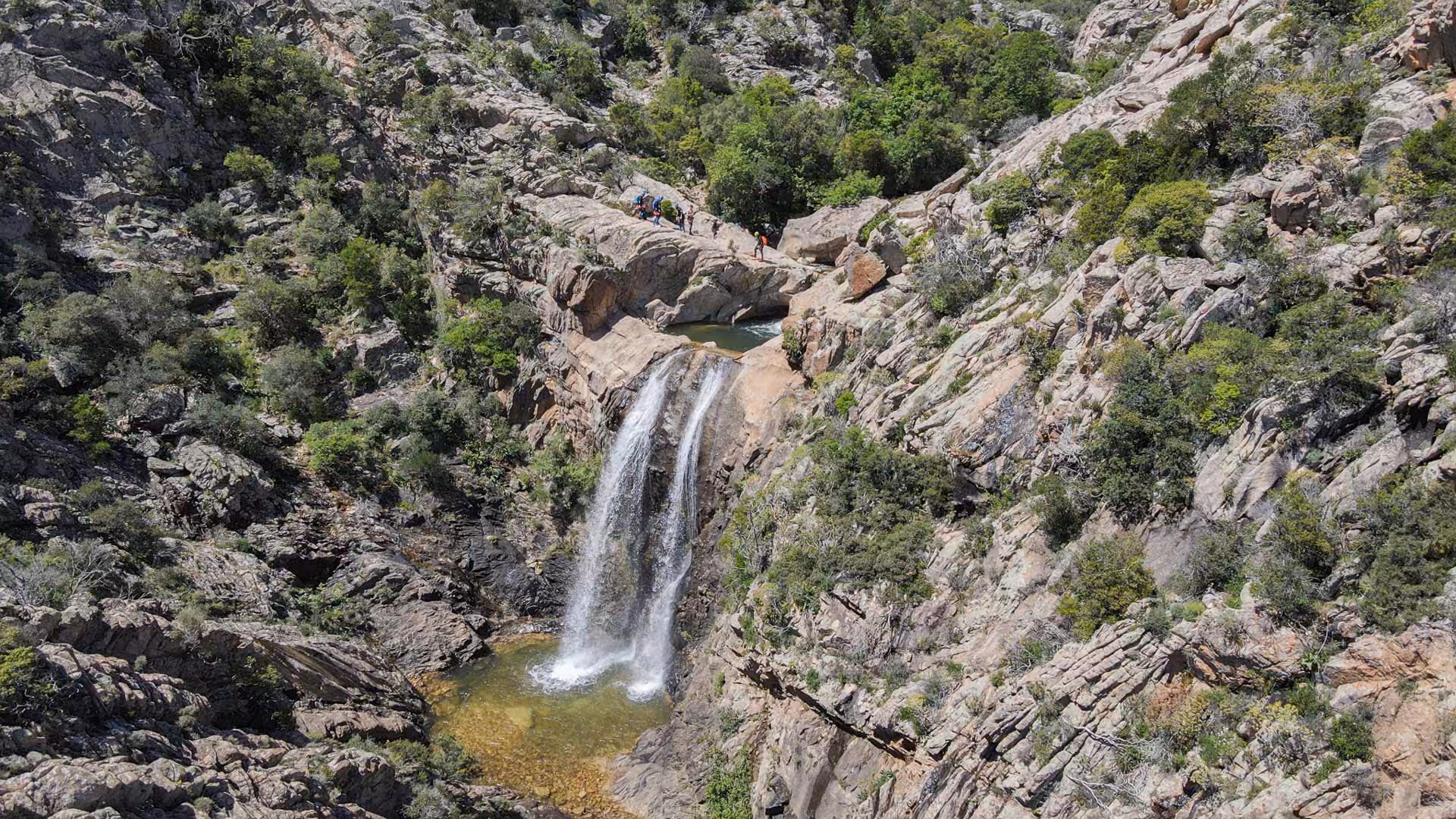 Stunning view of Rio Pitrisconi waterfall surrounded by lush greenery, ideal for San Teodoro canyoning adventure.