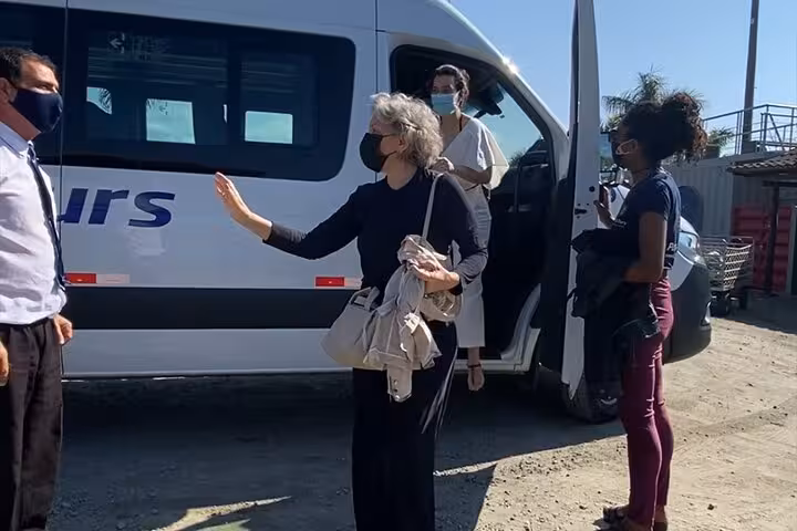 Passengers with masks interacting outside a shuttle in Rio, preparing for a shared ride to Angra dos Reis, Brazil.