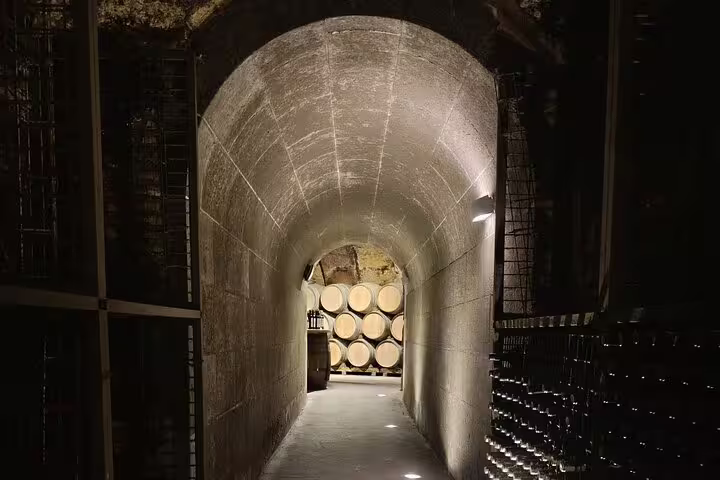 Dimly lit stone wine cellar tunnel in Rioja with barrels at the end, showcasing traditional winemaking.