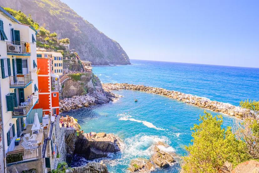 Scenic coastline view of Riomaggiore with vibrant buildings and clear blue sea in Cinque Terre.