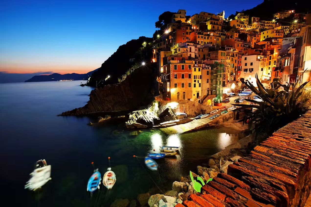 Riomaggiore harbor glowing at blue hour with fishing boats and illuminated houses on a Cinque Terre private tour