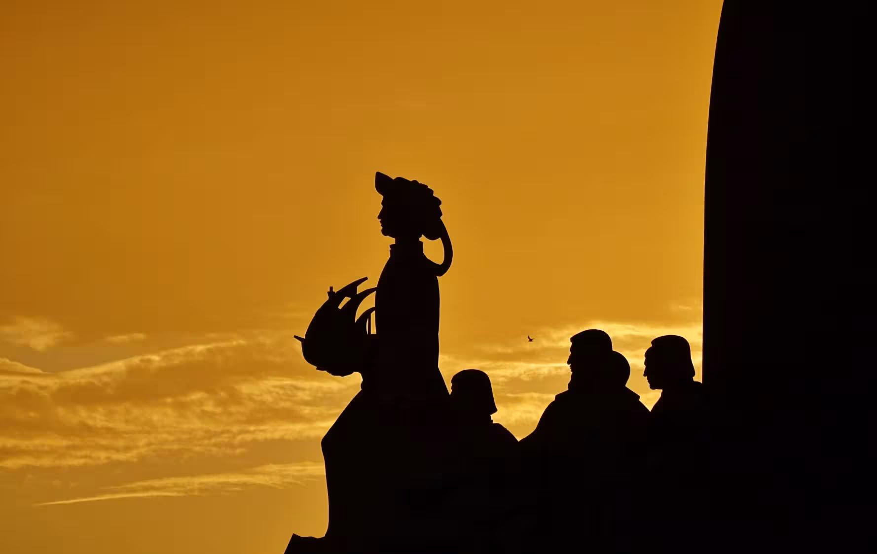 Silhouette of explorers at sunset, highlighting a scenic view from the River Light Bike Tour in Lisbon.