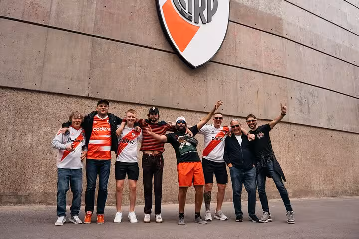 River Plate supporters pose by El Monumental exterior crest before Buenos Aires matchday tour