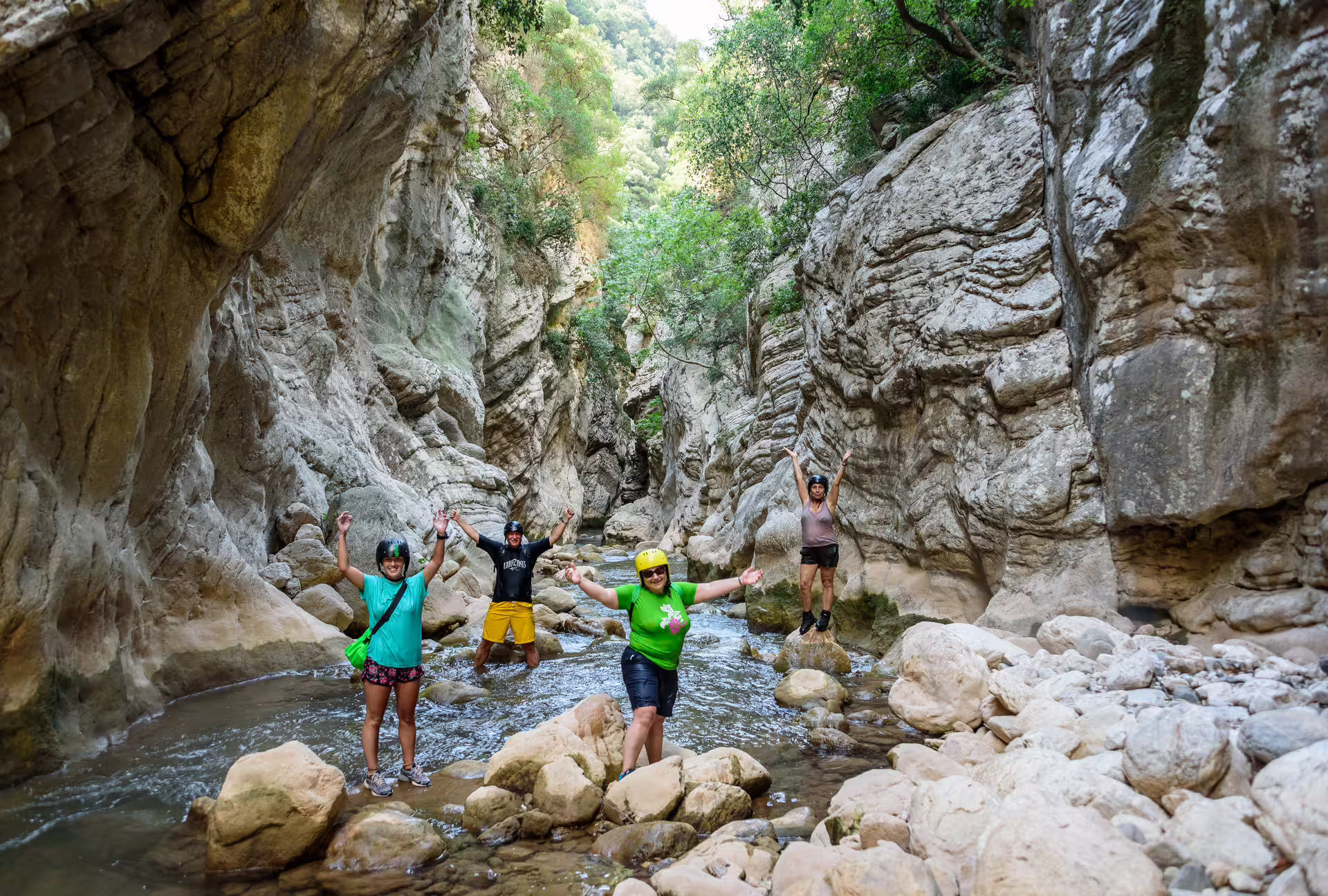 Happy hikers on River Trekking Neda tour crossing a rocky stream in the Neda River gorge canyon, Peloponnese