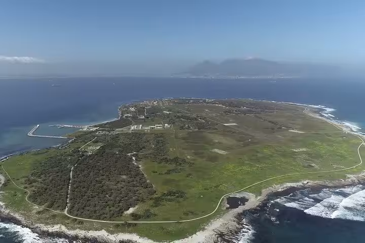 Aerial view of Robben Island's scenic landscape surrounded by ocean, highlighting its historical significance.