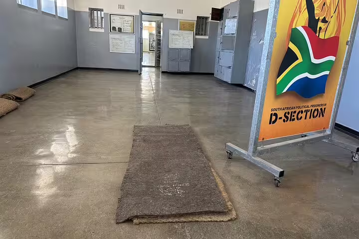 Interior view of Robben Island's D-Section with informational displays and South African flag imagery.