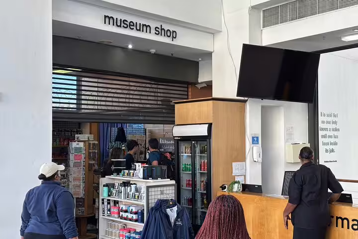 Visitors explore the museum shop at Robben Island tour departure point, offering souvenirs and refreshments.