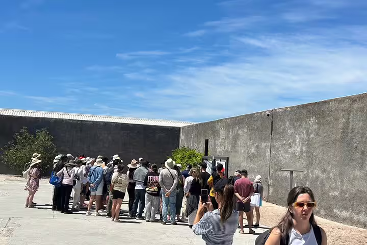 Tour group exploring the historic grounds of Robben Island under a clear blue sky, highlighting cultural heritage.