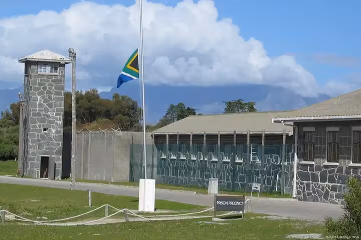 View of Robben Island prison with South African flag, highlighting historic tour site near Cape Town.