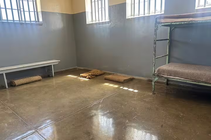 Sparse furnishings in a Robben Island prison cell, highlighting the austere conditions explored on this guided tour.