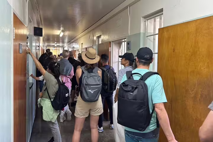 Visitors walk through Robben Island's historic prison corridor, experiencing a guided tour of its significant past.