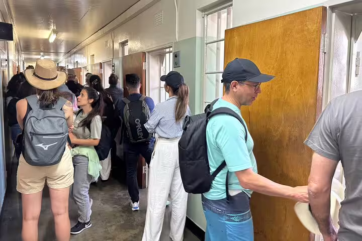 Tourists exploring the corridors of Robben Island prison, engaging with the rich history on a guided tour.