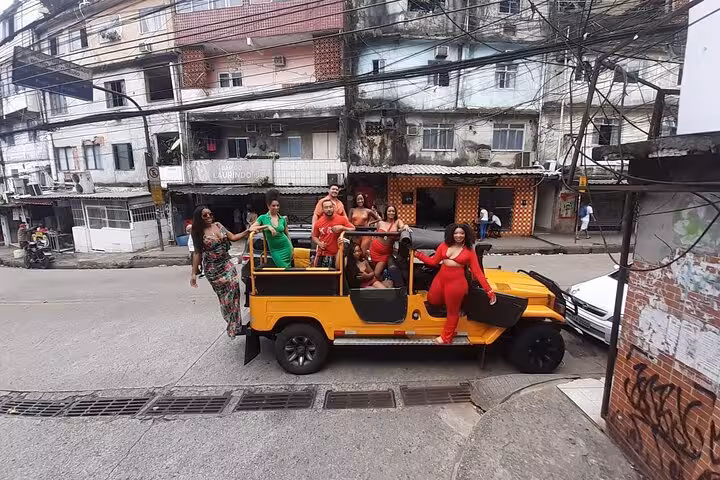 Visitors enjoying a Rocinha favela tour, standing on a yellow jeep with colorful local buildings in the background.