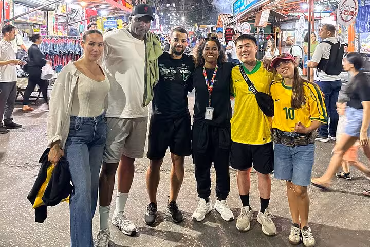 Group of tourists smiling and exploring the bustling streets of Rocinha, experiencing local culture and nightlife.