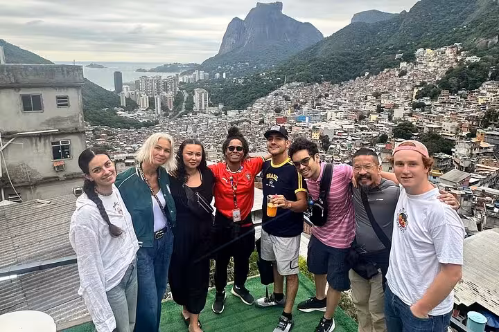 Visitors pose with a stunning view of Rocinha and Rio's mountains, capturing the essence of a favela tour.