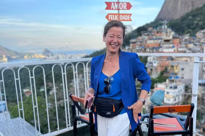Smiling tourist enjoying a scenic view from Rocinha favela's rooftop, showcasing vibrant community life in Brazil.