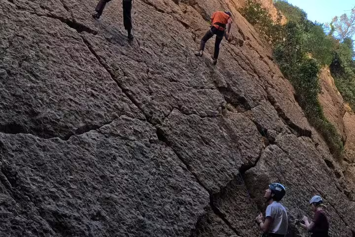 Group rock climbing up rugged cliff face on Lisbon adventure trail, enjoying outdoor challenge.