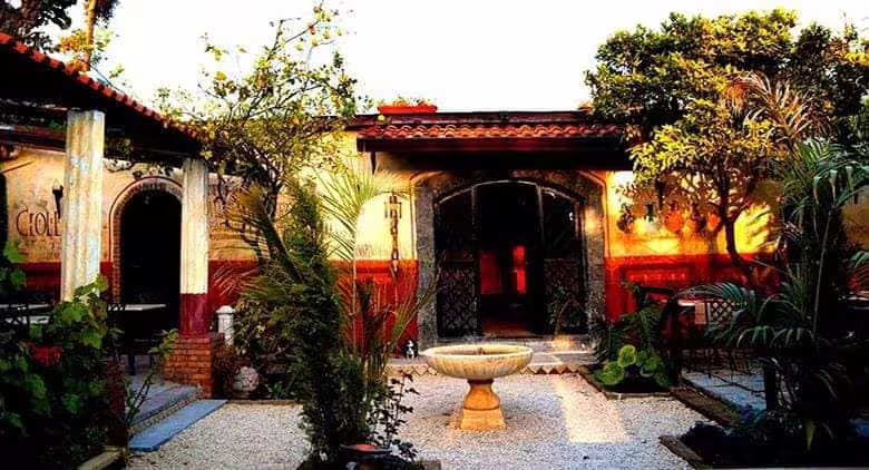 Sunlit courtyard of a historic Roman-style caupona with garden, fountain and rustic architecture for New Year’s Eve event