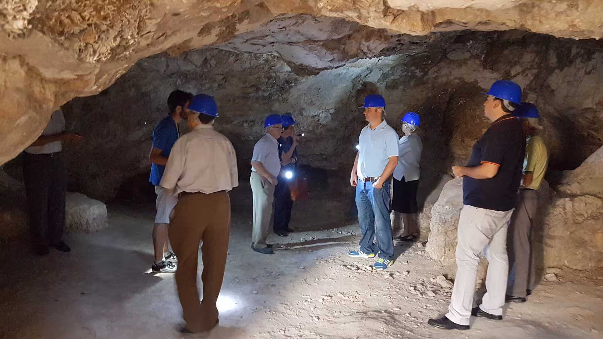 Guided visit inside Roman Empire mines near Madrid, tourists in helmets exploring ancient underground galleries