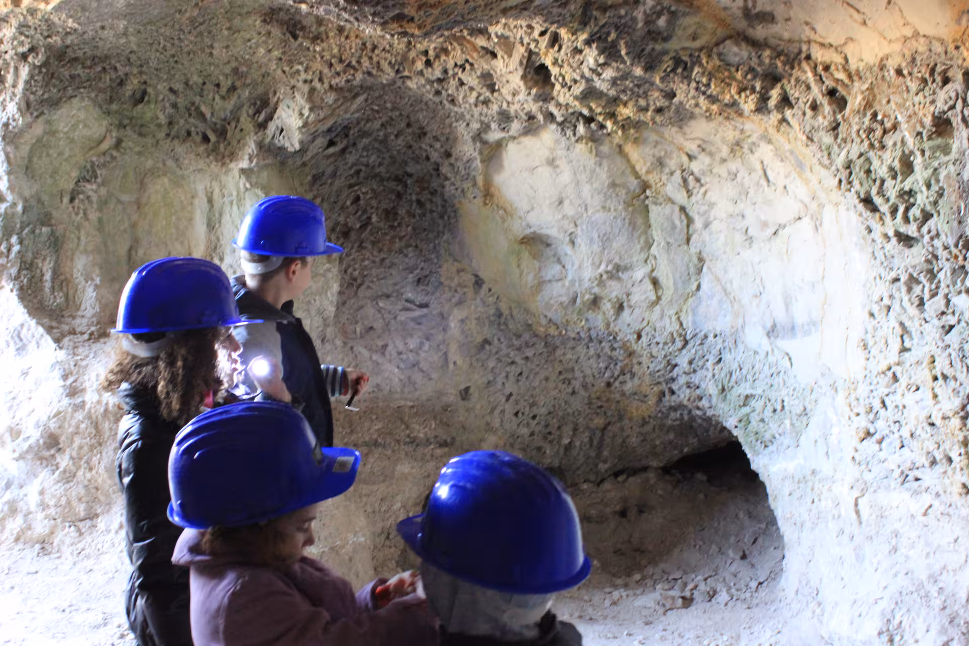 Visitors in helmets explore a Roman-era cave tunnel near Madrid on a one-day Roman Empire history tour