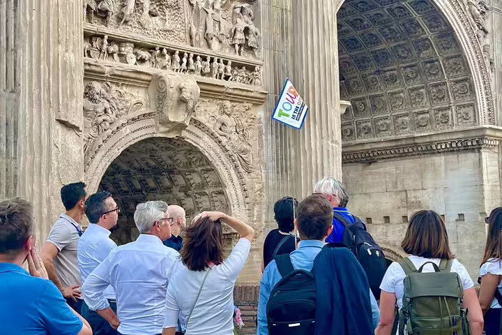 Tour group listening to guide at ornate triumphal arch near the Colosseum on a skip-the-line Roman Forum and Palatine Hill tour