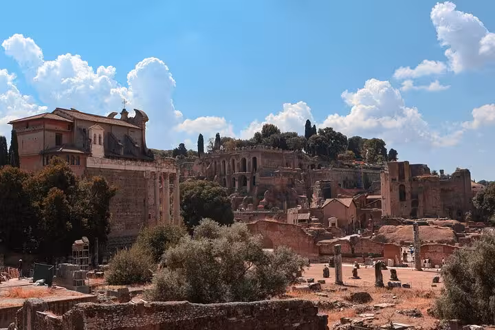 Scenic view of the Roman Forum ruins with ancient architecture under a vibrant blue sky in Rome, Italy.