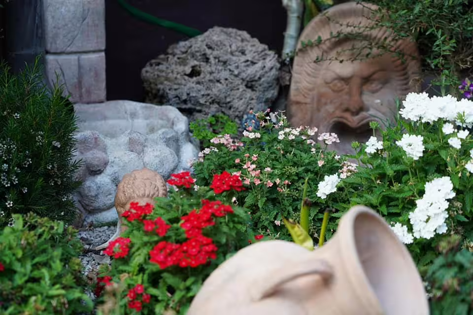 Lush Roman-style garden with terracotta masks, amphorae and colorful flowers at magical caupona New Year’s Eve venue