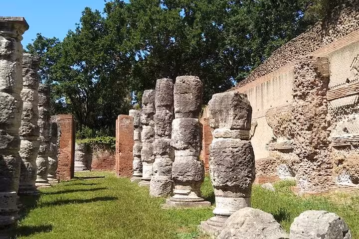 Ancient Roman ruins surrounded by lush greenery, showcasing historical architecture near Rome on a Vespa tour.
