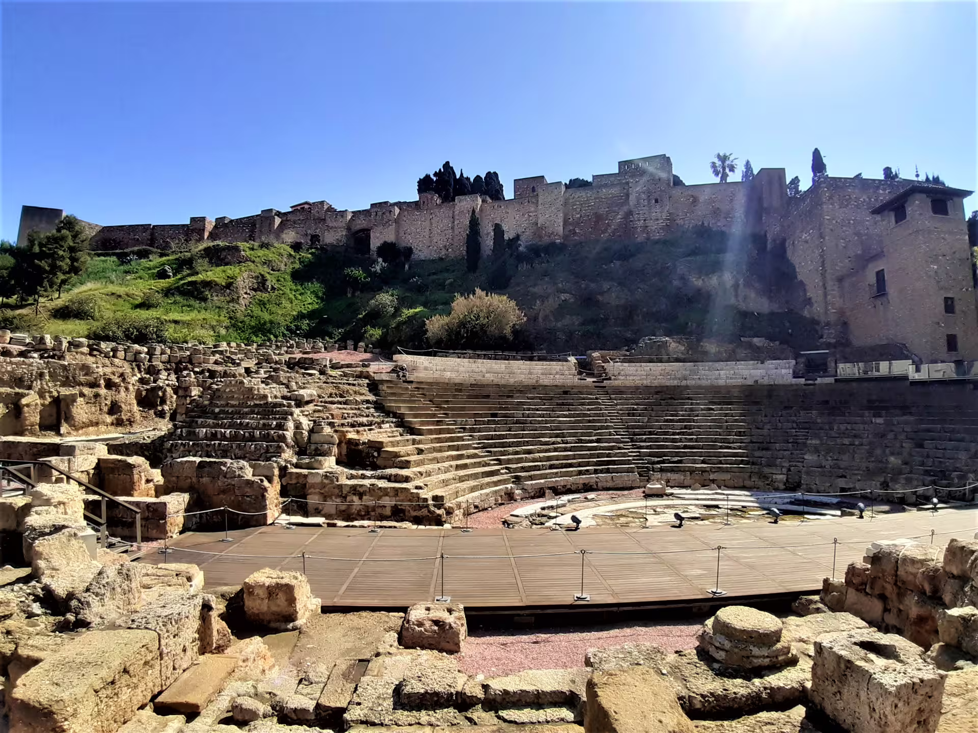 Roman Theatre of Malaga with Alcazaba walls under blue sky, private Marbella to Malaga day tour