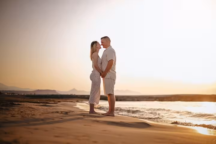Romantic couple standing on Gouves beach at sunset, embracing the moment during a private photoshoot session.