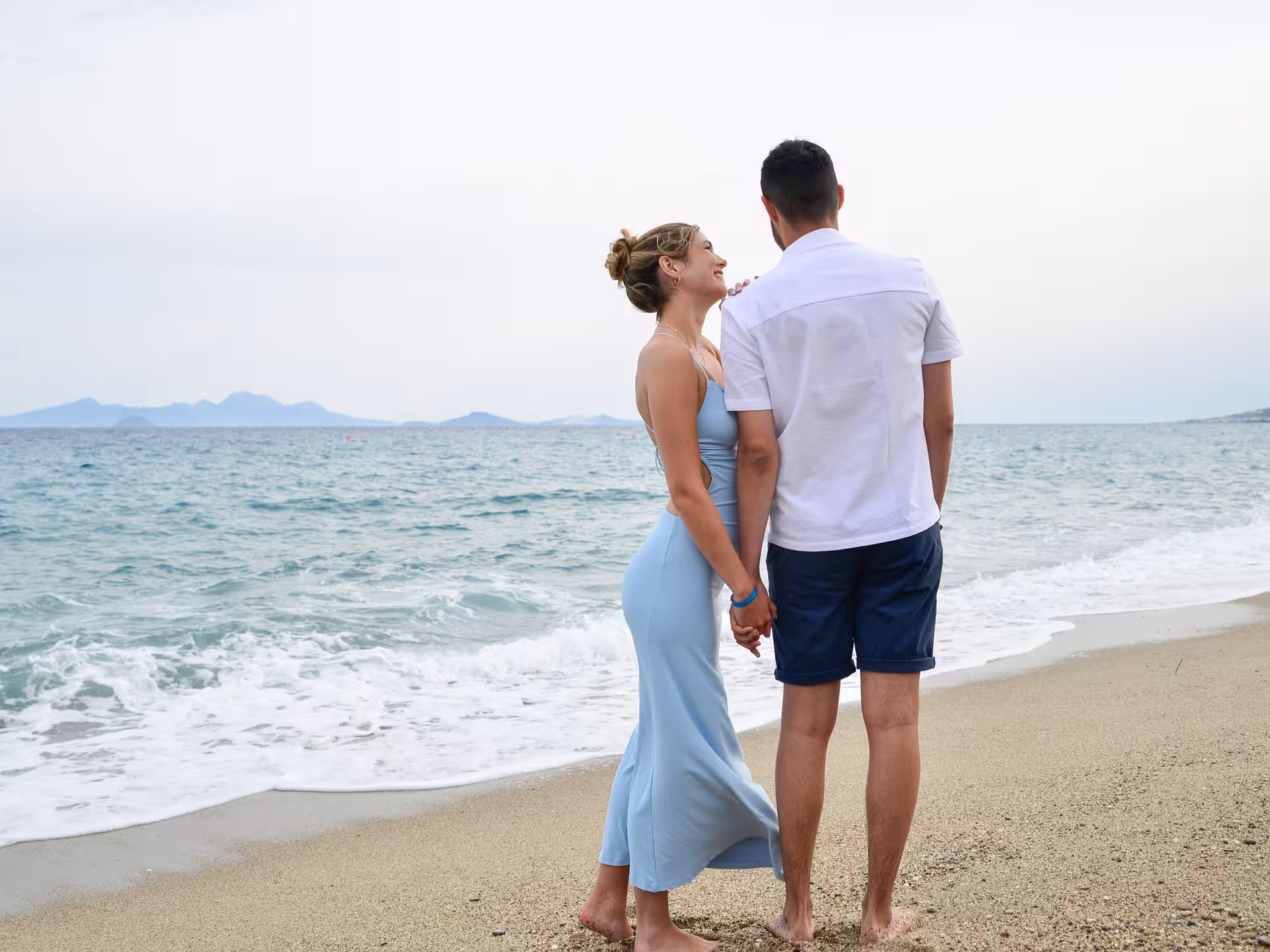 Romantic couple holding hands on the beach at Heraklion Venetian Port, ideal for a private photoshoot booking.