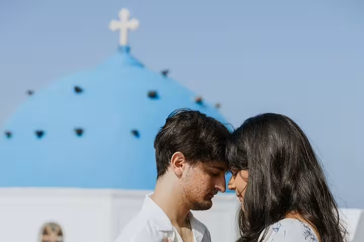 Romantic couple photo shoot in Santorini by blue-domed church, private honeymoon Instagram island tour
