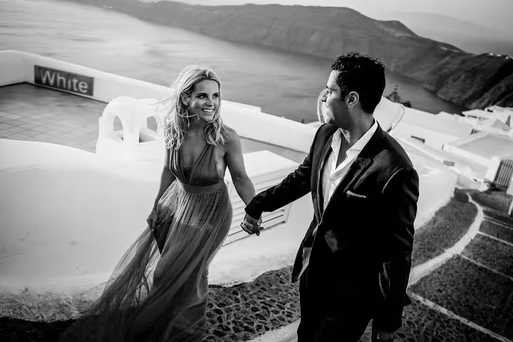 Romantic couple walking hand in hand on Santorini’s scenic paths with breathtaking sea views.