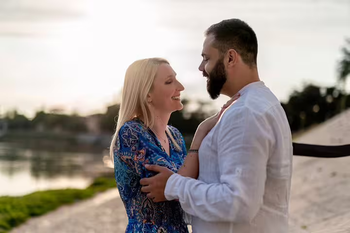 Happy couple sharing a moment by the river at sunset, ideal for a romantic professional photoshoot in Verona.