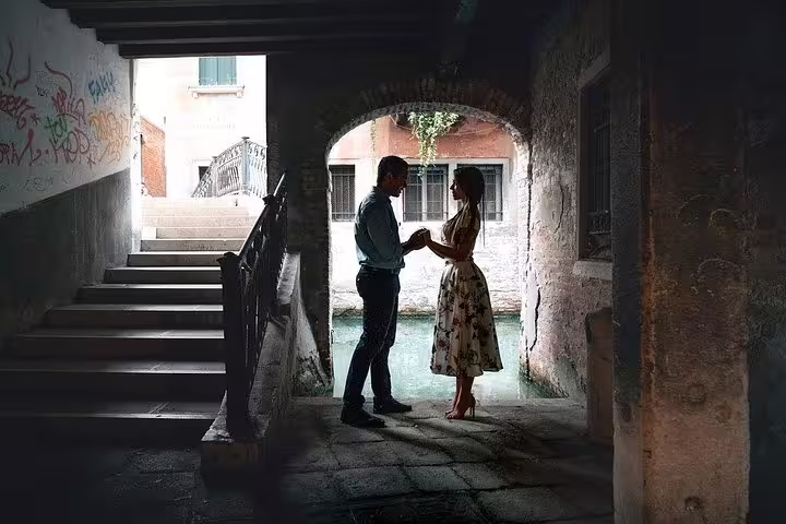 Romantic couple holding hands under a Venetian archway during a private photo shoot in Venice.