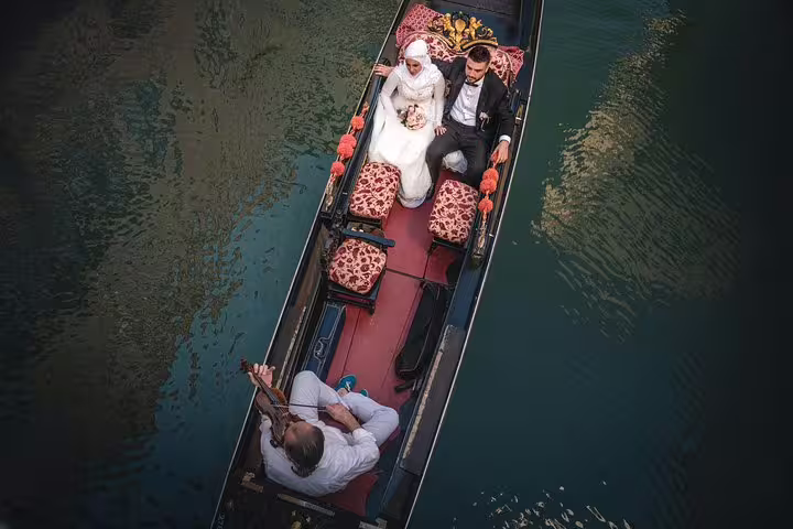Romantic gondola ride with a couple enjoying violin music and champagne in Venice's scenic canals.