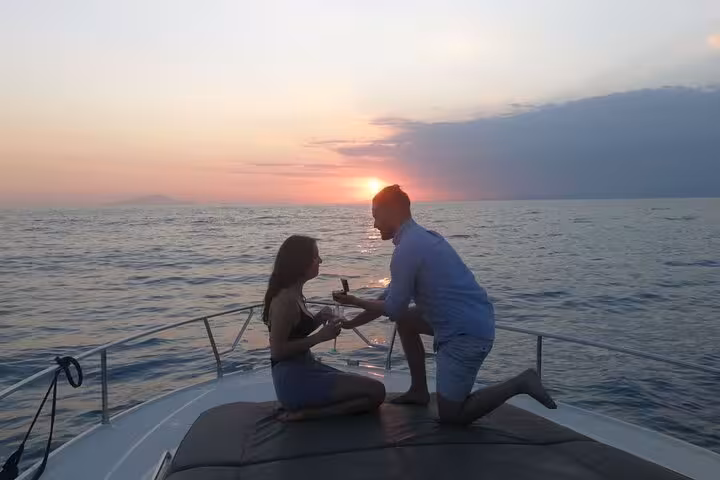 Couple enjoying a romantic proposal during a private sunset boat experience on the ocean, enhancing a memorable evening.