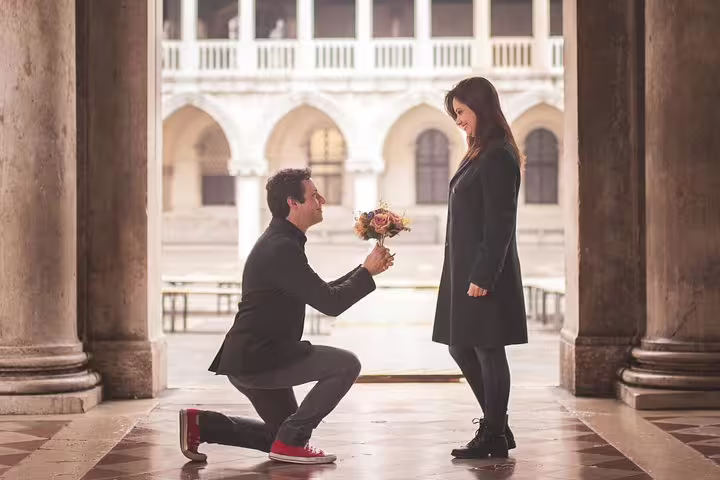Romantic Venice city portrait photo session capturing a proposal under arches with bouquet in soft light